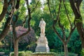 Scenic view of a white sculpture of a greek man standing in a park surrounded by nature