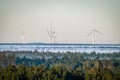 Scenic view of windmills behind green forests covered with fog in Osterild, Thy, Denmark Royalty Free Stock Photo