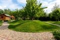 Scenic view yard garden trees and paved stone path road for walk against beautiful blue sky. Landscape design green lawn Royalty Free Stock Photo