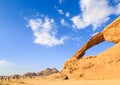 Scenic view of the yellow colored arch rock in the Wadi rum desert in Jordan witha group of persons on camels walking through