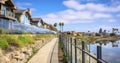 Scenic waterfront residential landscape. Pathway along homes with glass fences under skyscape of blue sky and clouds