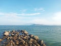 Scenic White Sand Beach with Wavy Water and Clear Blue Sky Background, Beautiful Seashore View with Mountains and stones in Summer Royalty Free Stock Photo