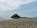 Scenic wide angle view of small tropical island at low tide sandy beach with cloudy sky in Endau, Malaysia