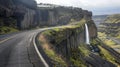 Scenic winding road with a waterfall cascading down a cliff face Royalty Free Stock Photo