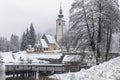 Scenic winter landscape of Bohinj lake in Gorenjska with old bridge and Church