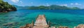 Scenic wooden walkway over turquoise ocean to overwater bungalows at tropical resort