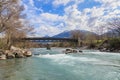 A scenics view of the Durance river flowing under a wooden walking bridge under a majestic blue sky