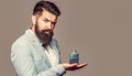Scent cologne bottle, male holding cologne. Masculine perfume, bearded man in a suit. Masculine perfume, bearded man in