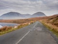 Scene in Connemara national park, Old asphalt road, sheep grazing grass, Beautiful mountains in the background. Cloudy sky Royalty Free Stock Photo