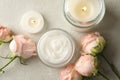 Scented candles, cosmetic cream and roses on white table