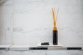 Scented diffuser stick in black glass bottle against white marble wall background Royalty Free Stock Photo