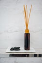 Scented diffuser stick in black glass bottle against white marble wall background Royalty Free Stock Photo