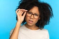 Sceptical mistrustful African American girl adjusts glasses, suspicious looking at camera. Studio. Royalty Free Stock Photo