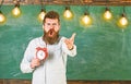 Schedule and regime concept. Teacher in eyeglasses holds alarm clock. Man with beard on shouting face on arguing