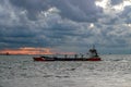 A sand dredger sails out to sea in the evening light.