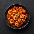 Schezwan Prawns in black bowl at dark slate background. Schezwan Prawns is indo-chinese cuisine curry dish