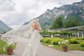 Bride in a lace dress with a veil flying in the wind against the backdrop of a beautiful alpine landscape, selective focus