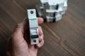 Schneider Electric electric relay and automatic machines in a man's hand. Wooden background.