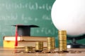 Scholarship concept. Graduation cap, books, globe and coins on wooden table Royalty Free Stock Photo