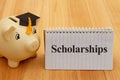 Scholarships message with gold piggy bank with a grad cap on wood desk Royalty Free Stock Photo