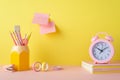 School accessories concept. Photo of alarm clock over copybooks pencil holder adhesive tape mini stapler and sticky note paper Royalty Free Stock Photo