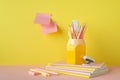 School accessories concept. Photo of stationery on pink desk pencil holder stack of notebooks pens mini stapler eraser and sticky Royalty Free Stock Photo