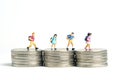 School admission budget. Children or kids, walking above golden coin money stack. Miniature tiny people toys photography.