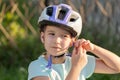 School age biker, child taking off or putting on a protective biking helmet, young cyclist portrait, face closeup fastening helmet