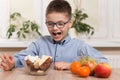 The school-age boy smiles and holds a dish with sweets and a sugar bowl with sugar cubes. Next to it, on the table top are mandari