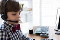 School-age boy wearing red bow tie and headset typing on keyboard in home office, copy space Royalty Free Stock Photo