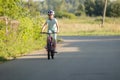 School age child on a bike, girl biker riding through an empty street in a rural area, one person, front view, copy space. Biker