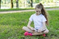 A school-age girl reading a book sitting on the grass in the park Royalty Free Stock Photo