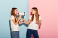 School age girls, sisters friends wearing white t-shirts and jeans communicate isolated over pink-blue background Royalty Free Stock Photo