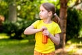 School age young child, happy little girl opening a glass bottle full of healthy orange carrot juice, simple outside outdoors Royalty Free Stock Photo