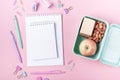 School background with notebooks and pastel colorful study accessories on pink background Lunch box with apple, sandwich