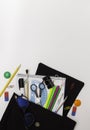 School background. Office supplies in an open black backpack. White background, free space for text Royalty Free Stock Photo