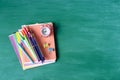 School supplies, pens, pencils, notebooks and an alarm clock on a  against the background of a green school board Royalty Free Stock Photo