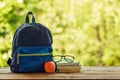 School backpack with books on wooden table and nature background Royalty Free Stock Photo