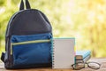 School backpack with books on wooden table and nature background Royalty Free Stock Photo