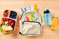 School backpack with supplies, kids lunch box with sandwich, fruits, vegetables, bottles of water and juice on wooden table Royalty Free Stock Photo