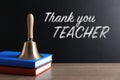 School bell and books on wooden table near blackboard with phrase Thank You Teacher Royalty Free Stock Photo