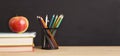 School books, apple and pencils over chalkboard background Royalty Free Stock Photo