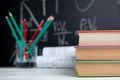 School books, pencils and drawings on white table on blackboard background Royalty Free Stock Photo