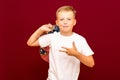 School boy with backpack, on red wall shows with three fingers