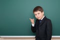 School boy in black suit show finger gesture, on green chalkboard background, education concept Royalty Free Stock Photo