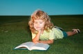 School boy with a book having a rest outdoor. Child boy with a book in the garden. Kid is readding a book playing Royalty Free Stock Photo