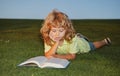 School boy with a book having a rest outdoor. Child boy is reading a book on the spring park. Relaxing on the grass in Royalty Free Stock Photo