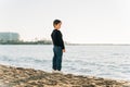 School boy child enjoying winter sea view from a sandy beach. Kid standing on shore watching autumn ocean waves. Royalty Free Stock Photo