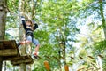 School boy in forest adventure park. Acitve child, kid in helmet climbs on high rope trail. Agility skills and climbing