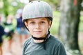 School boy in forest adventure park. Acitve child, kid in helmet climbs on high rope trail. Agility skills and climbing